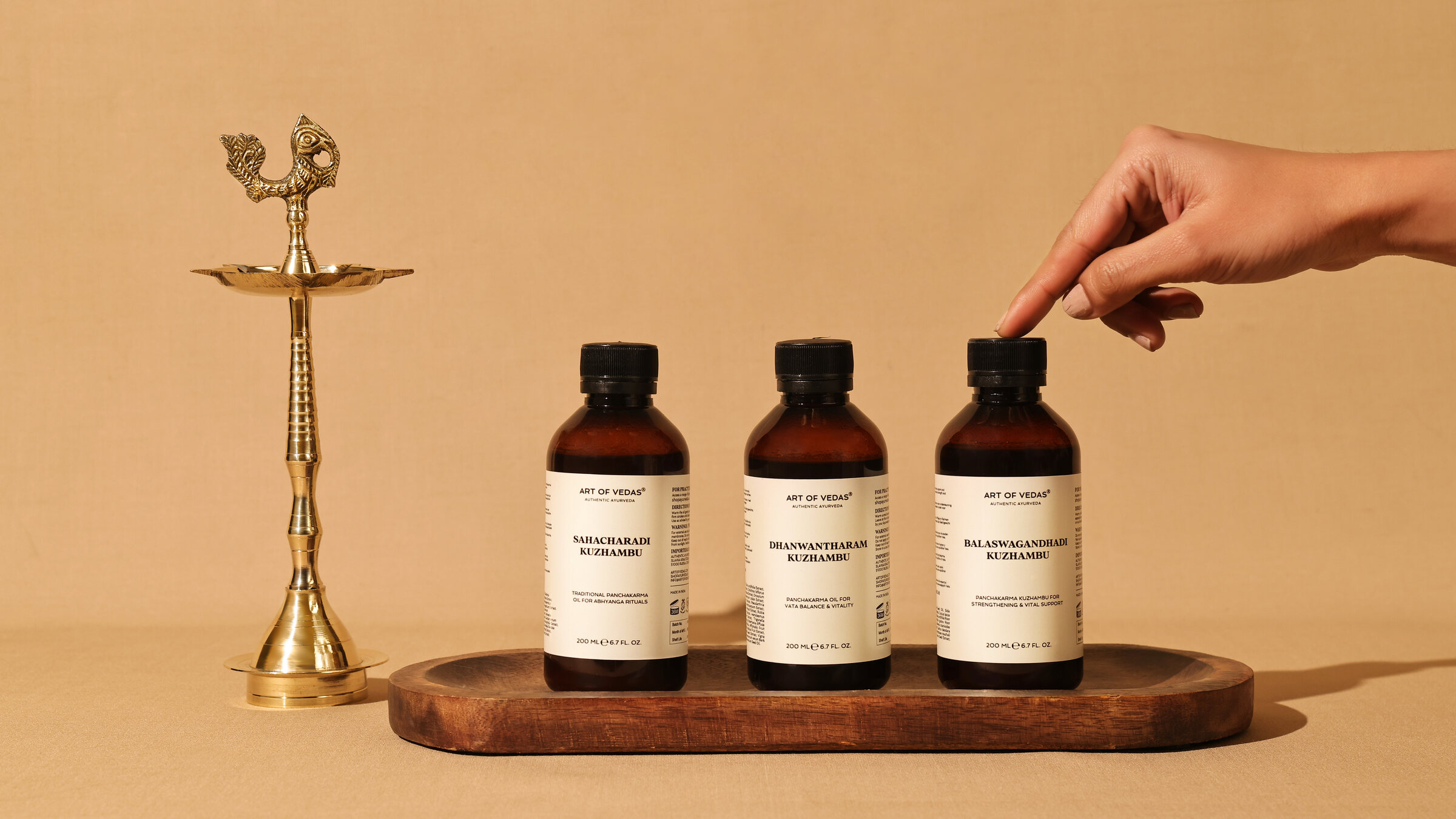 Art of Vedas Kuzhambu bottles with a brass ritual lamp on a wooden tray